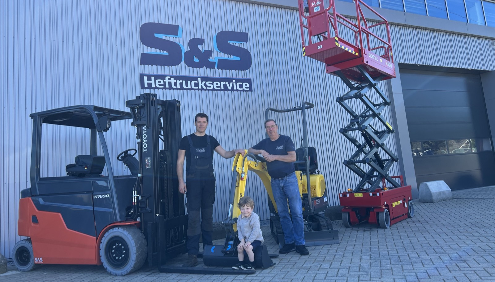 Twee medewerkers van S&S Heftruckservice voor de eigen hal in Maastricht, met een Toyota-heftruck, een minigraver en een schaarhoogwerker